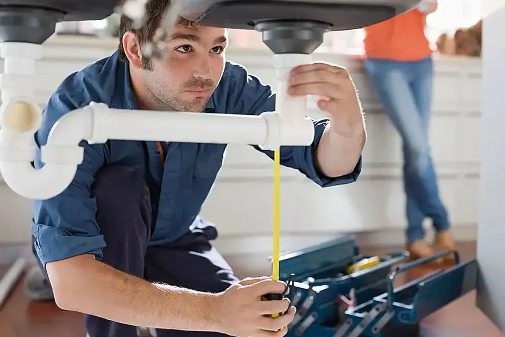 Plumber inspecting kitchen sink drain pipes during a drain cleaning service in Toronto
